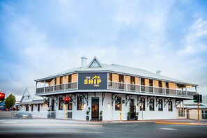 A two-story building with a balcony and a sign that reads "The Ship Inn". - Nightcap at the Ship Inn (Busselton)