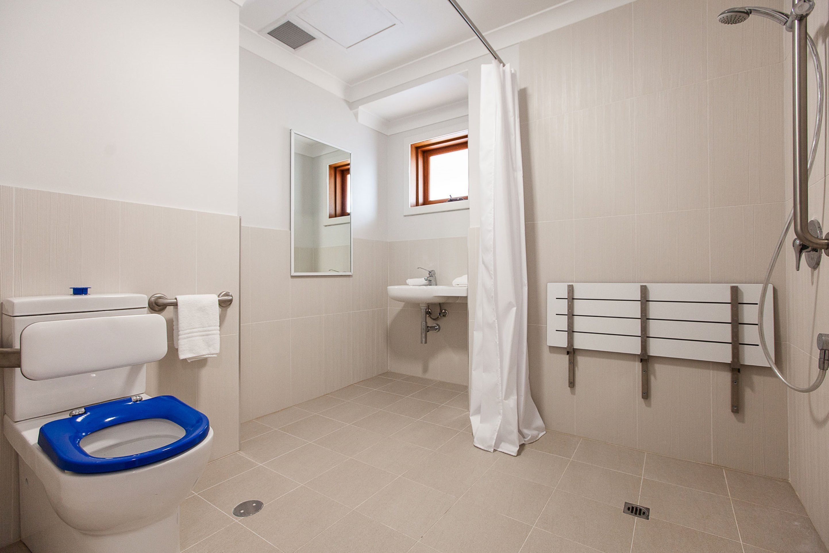 Un baño con inodoro blanco, lavamanos, ducha y espejo.