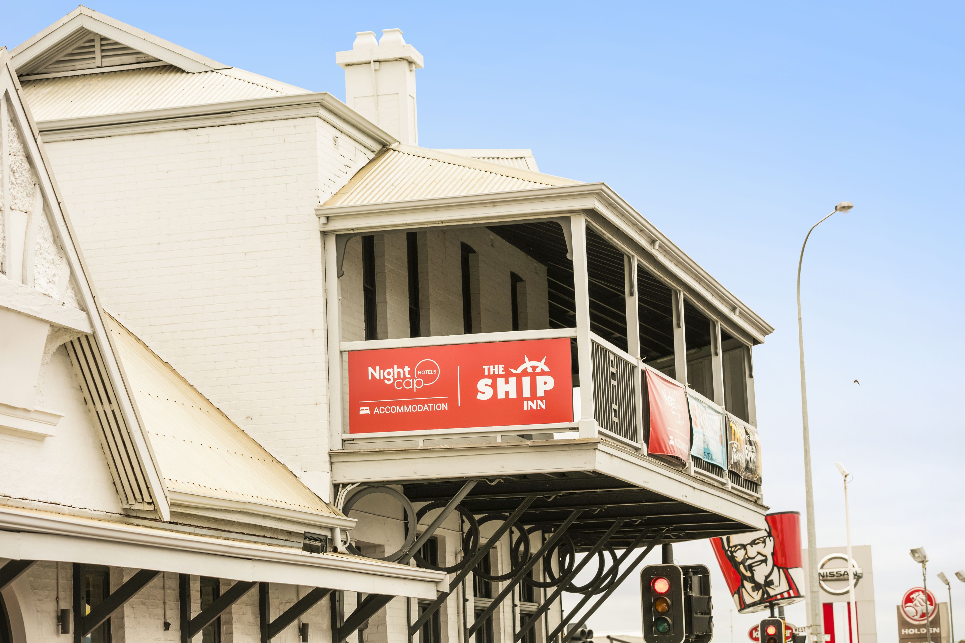 A building with a balcony advertising 'Nightcap The Ship Inn' accommodation.