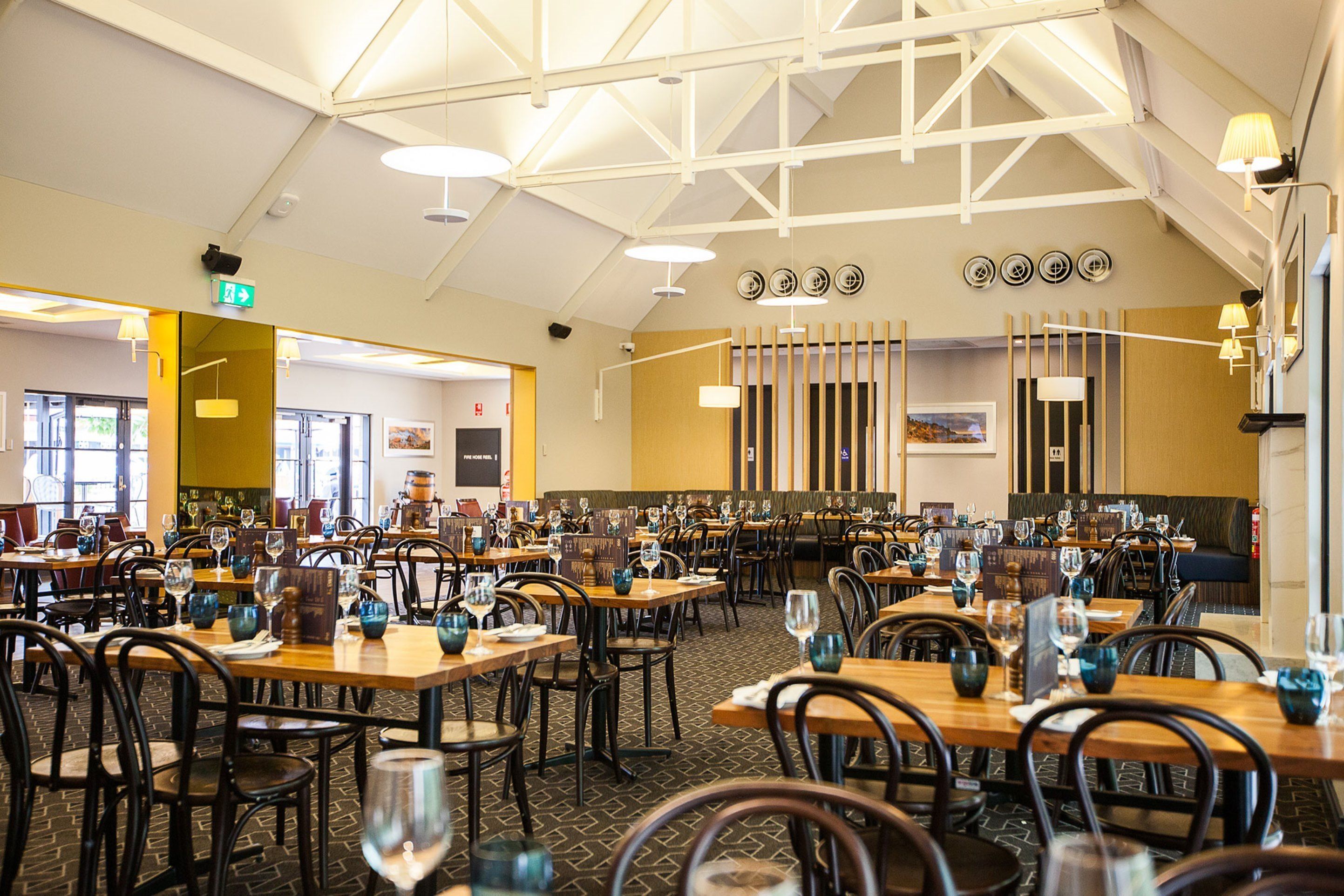 Un restaurant spacieux, doté de nombreuses tables et chaises, de hauts plafonds et d’un éclairage moderne.