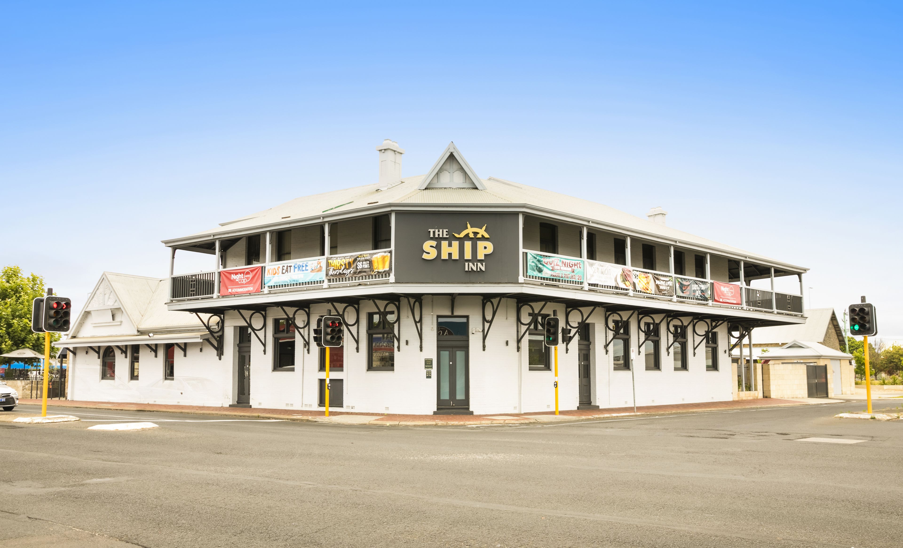 A two-story building with a sign reading "The Ship Inn" and multiple banners advertising specials.