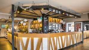 Un espace bar avec un comptoir, des étagères remplies de bouteilles et un panneau indiquant « Bière du mois ».