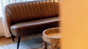 Un sofá de cuero marrón con una alfombra de tonos claros y una mesita de madera.