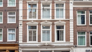 Un edificio de dos pisos con un letrero que dice "DREAM HOTEL", que presenta un estilo arquitectónico clásico con ventanas simétricas y una entrada central.