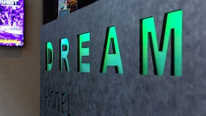 Una recepción con la palabra "DREAM" iluminada en letras verdes, que indica el nombre del hotel.