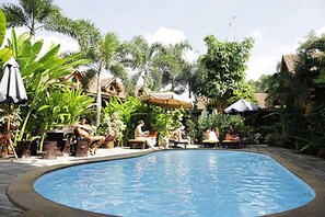 A swimming pool surrounded by lush greenery and outdoor seating areas. - Loghome Boutique (Chiang Mai)