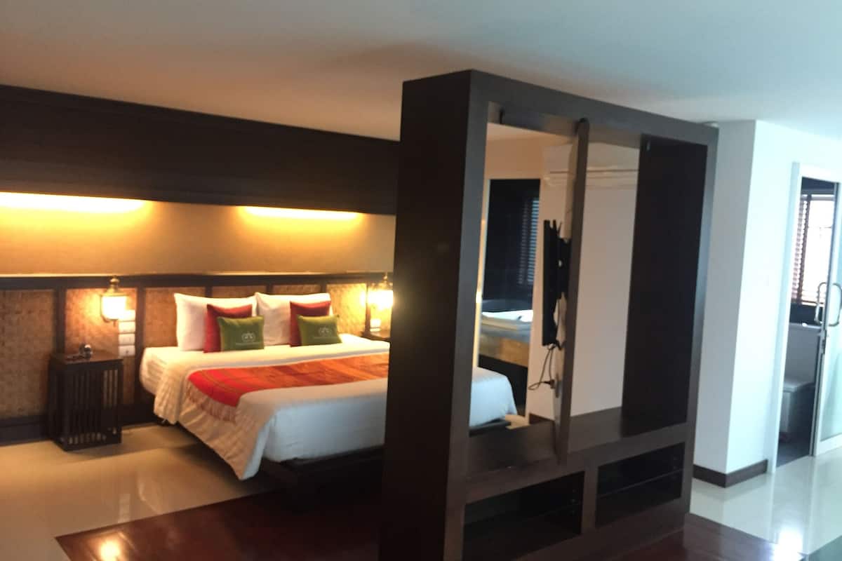 A hotel room with a large bed, bedside tables, a mirror, and a view of the outside.