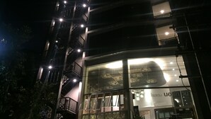 Un edificio de varios pisos con balcones iluminados y fachada de vidrio.