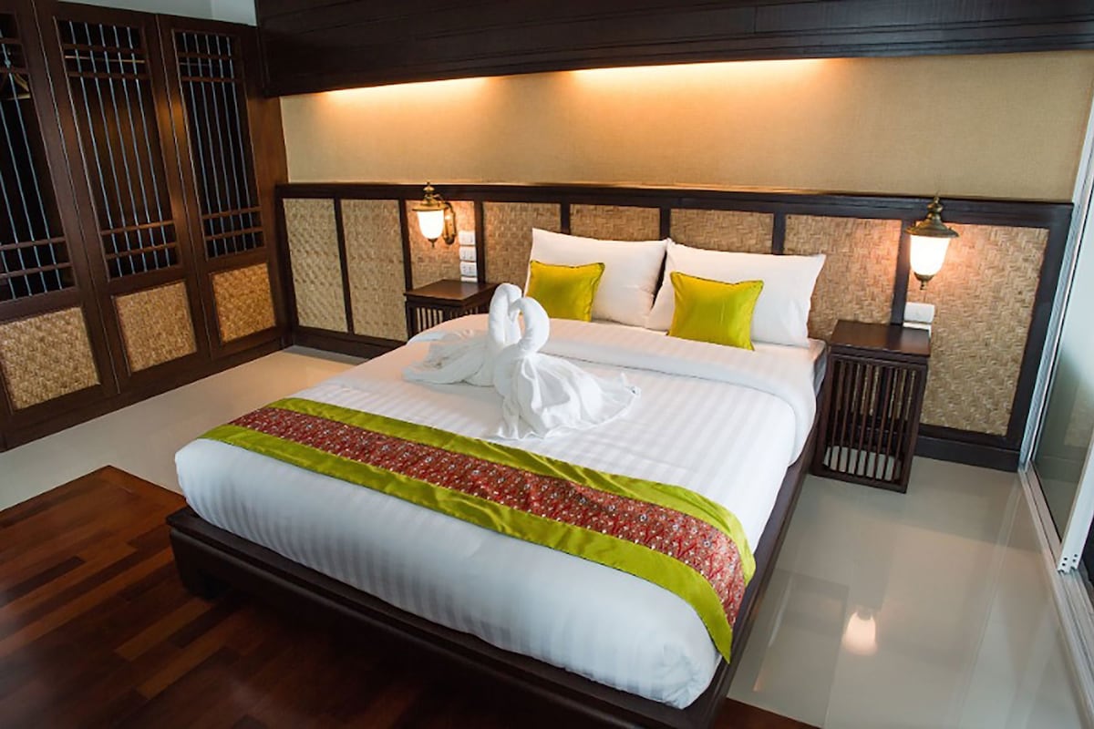 A hotel room with a large bed, two nightstands, a wooden headboard, and a decorative wall panel.