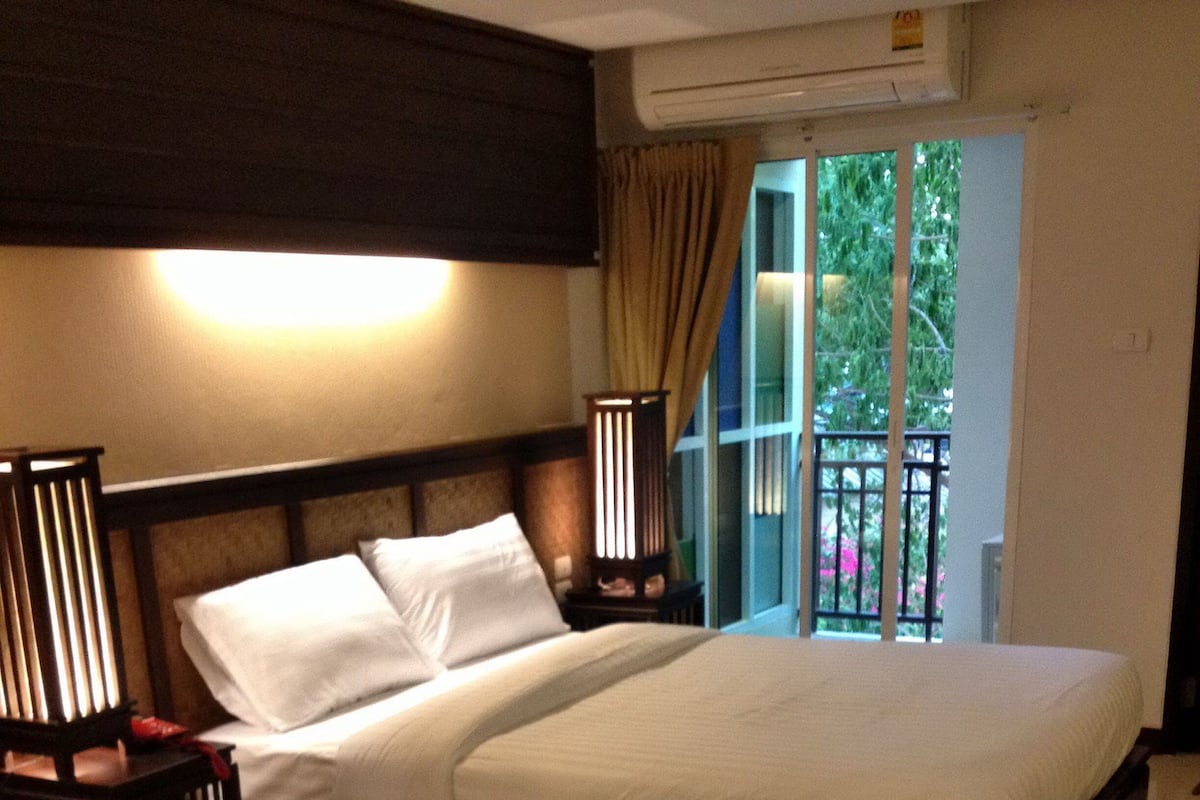 A neatly made bed with white linens, a dark headboard, and two bedside lamps.