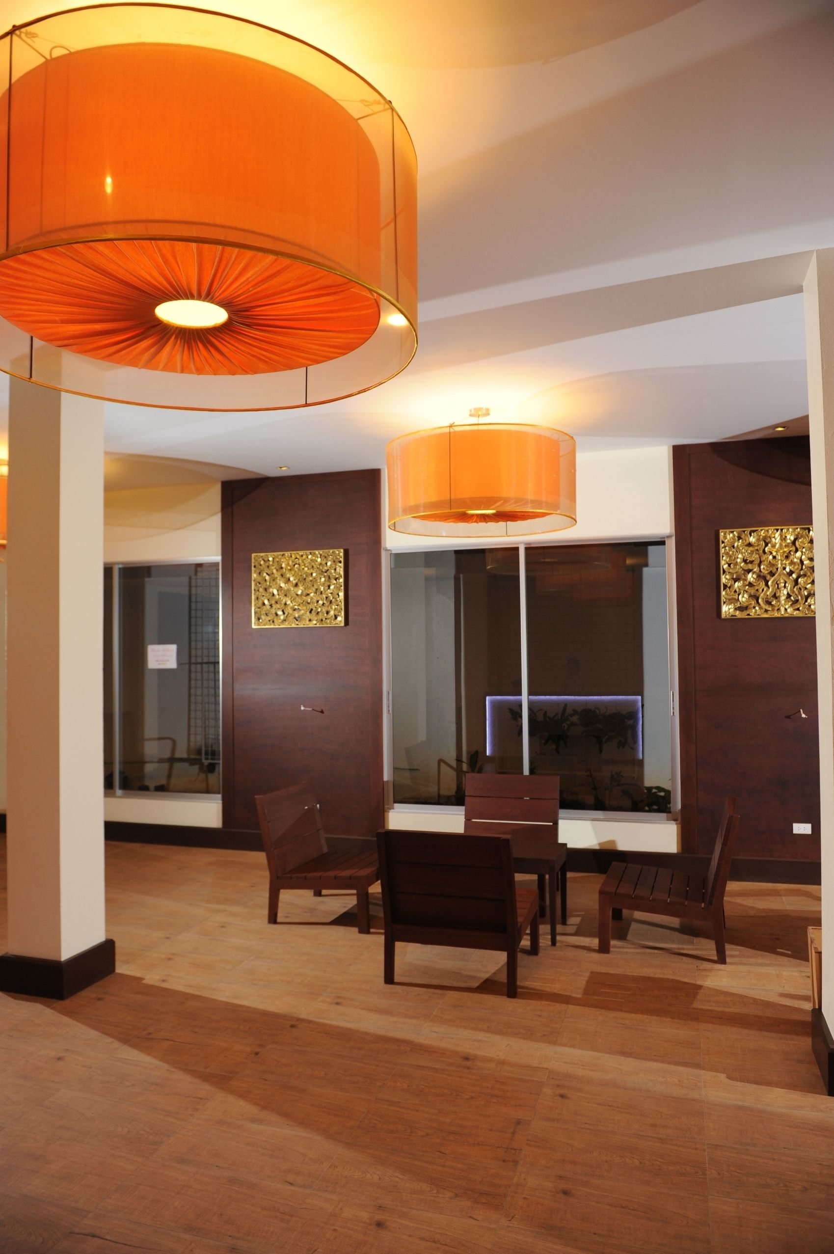 A modern interior with wooden flooring, a dining area with chairs and a table, and two large orange lamps.