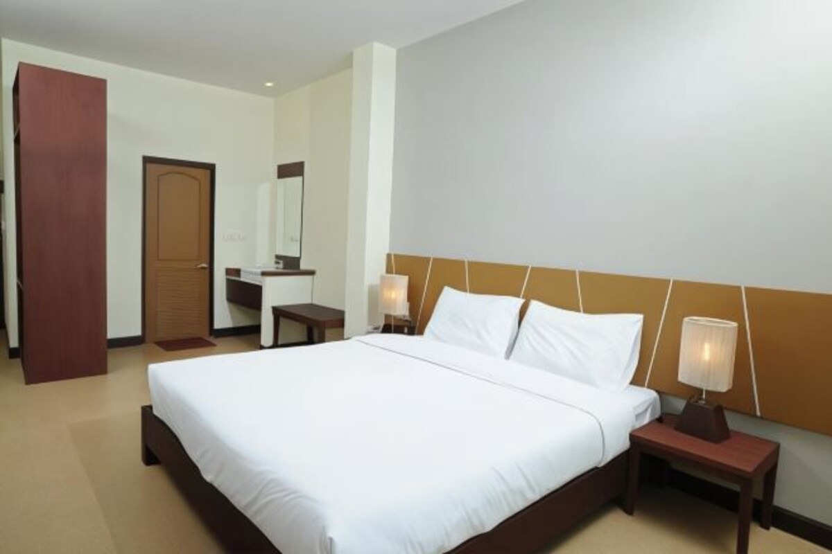 A hotel room with a large bed, bedside tables, a mirror, and a wooden door.