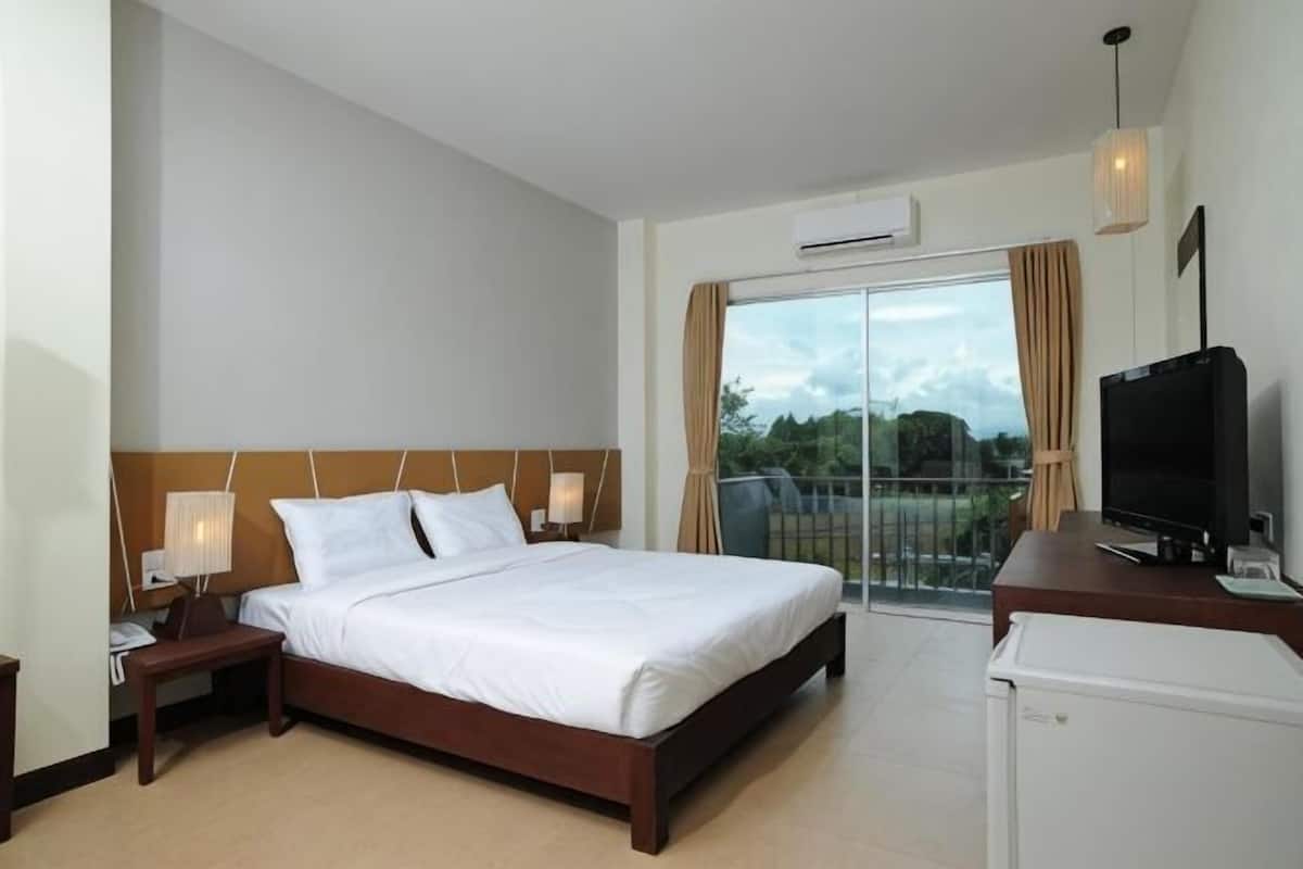 A hotel room with a bed, a TV, a desk, and a balcony with a view.
