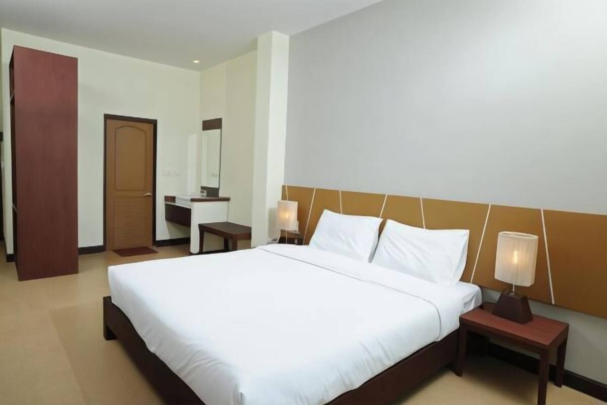 A hotel room with a large bed, bedside tables, a mirror, and a wooden door.