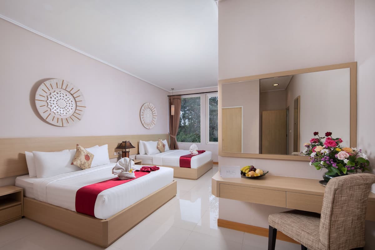 A hotel room with two beds, a desk, a chair, a mirror, and a vase of flowers.