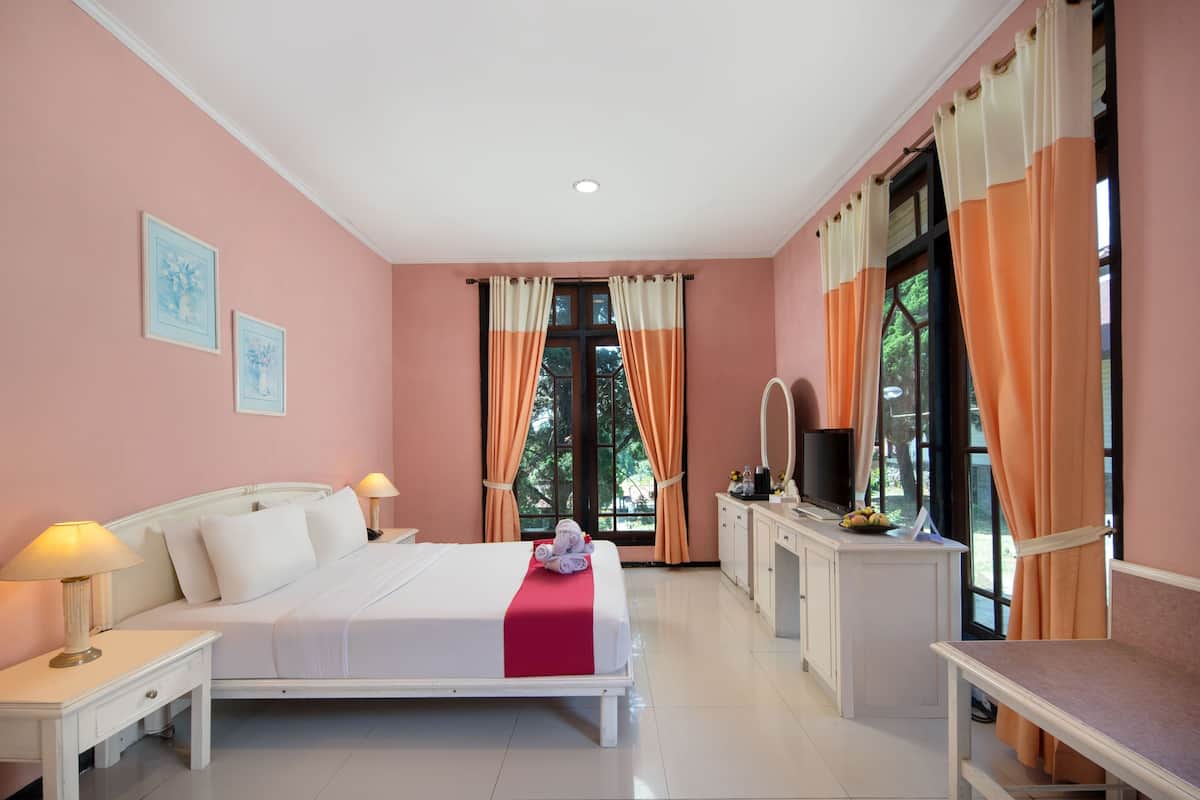 A bedroom with a bed, bedside tables, a desk, a mirror, and a window with curtains.
