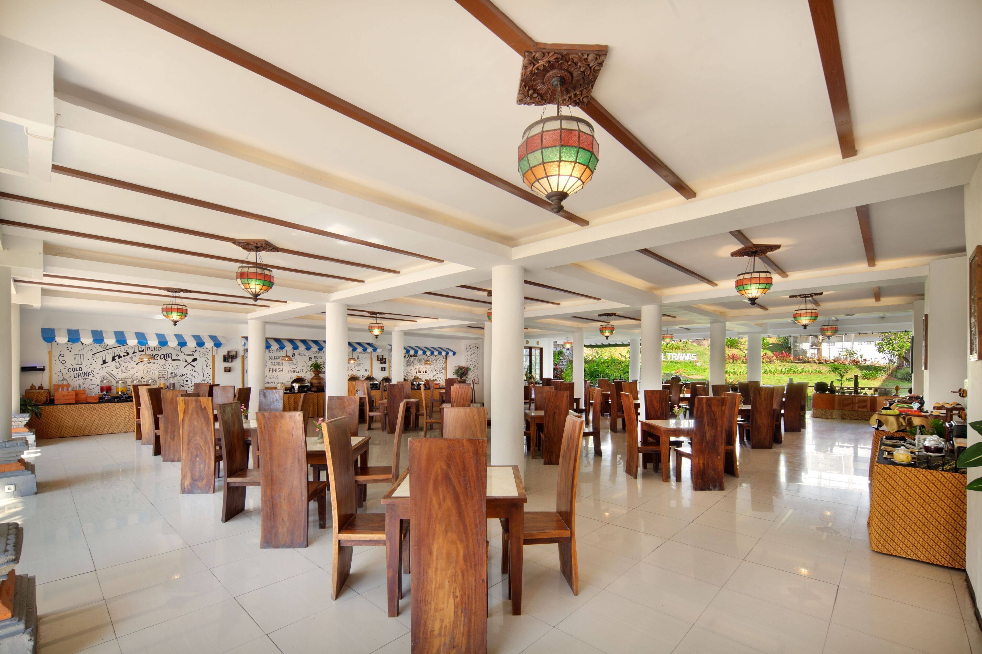 A spacious restaurant with wooden tables and chairs, hanging decorative lights, and a mural on the wall.