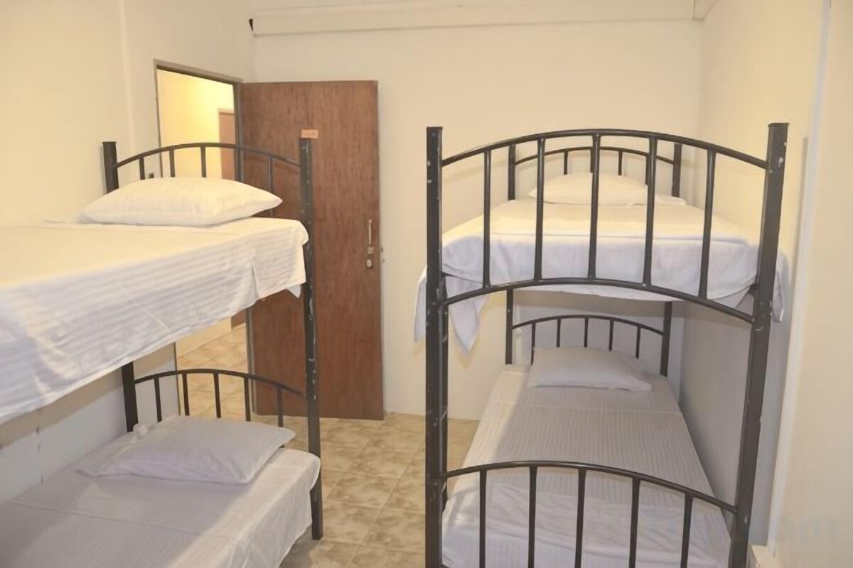 A dormitory room with bunk beds, a wooden door, and a tiled floor.