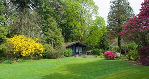 A cabin surrounded by lush greenery and vibrant flowers.