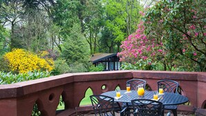 A patio with a round table and chairs, surrounded by a brick wall with cut-out designs. - Brockwood Hall (Millom)