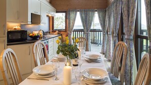 A dining table set for a meal with white plates, cutlery, and a candle centerpiece. - Brockwood Hall (Millom)