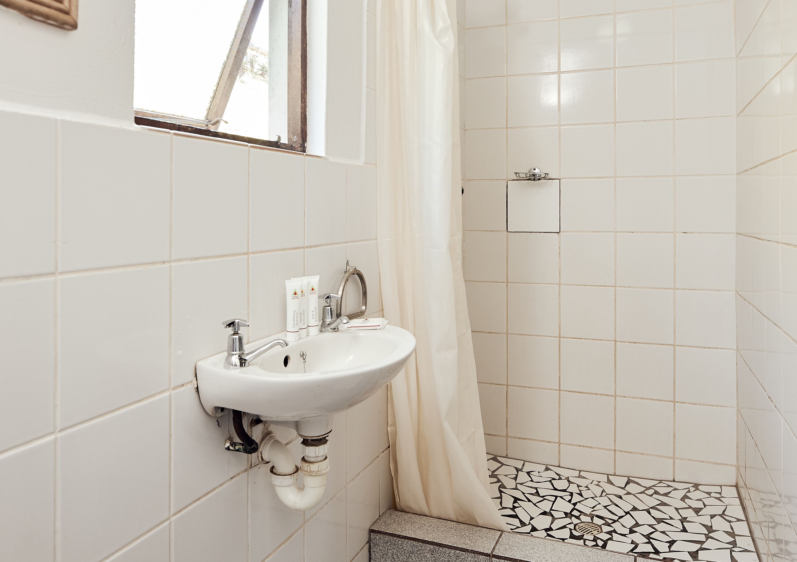 A bathroom with a white sink, a shower curtain, and a tiled floor with a geometric pattern.
