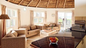 A spacious living area with a large island, a sofa, and a dining table. - First Group Hole in the Wall (King Sabata Dalindyebo)