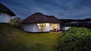 A thatched-roof house with a dining area and a small garden. - First Group Hole in the Wall (King Sabata Dalindyebo)