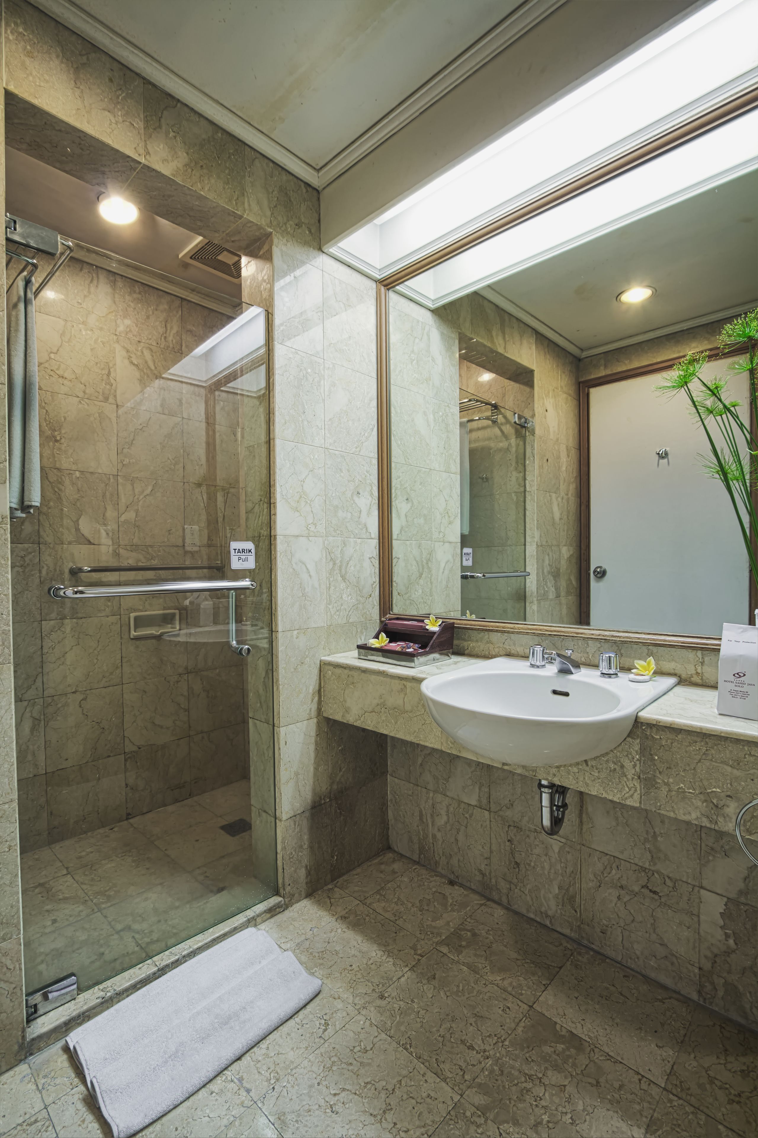 Un baño moderno con ducha de vidrio, un lavabo con espejo y una toalla en el suelo.