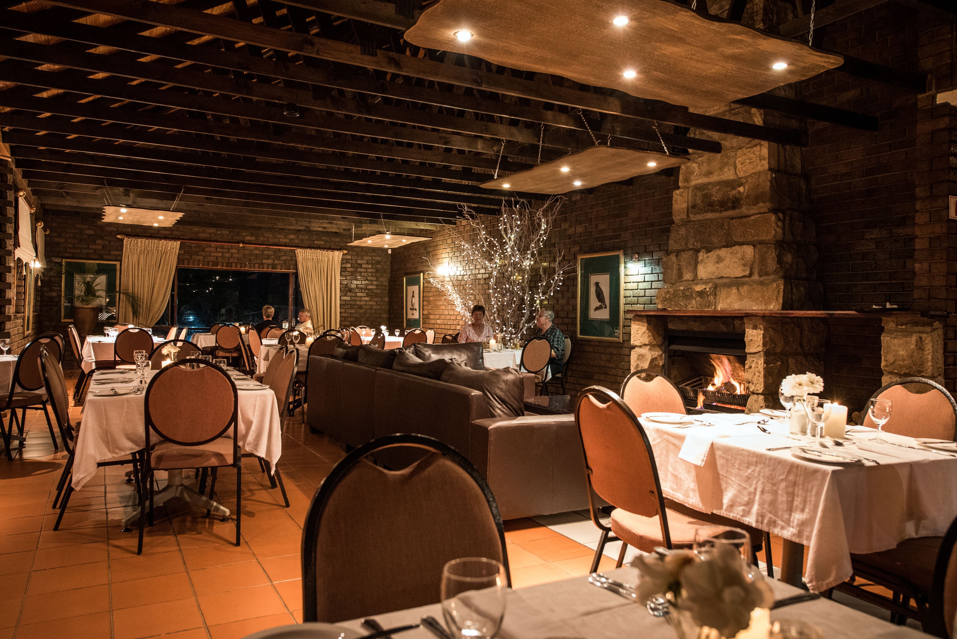 Un restaurante con varias mesas y sillas, una chimenea y una pared de ladrillo.