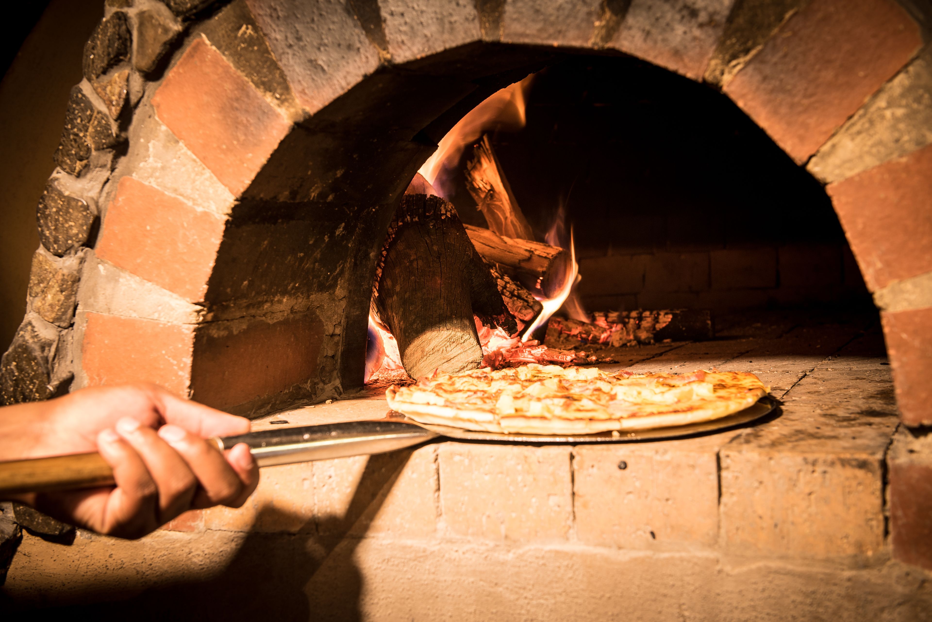 A pizza being removed from a brick oven.