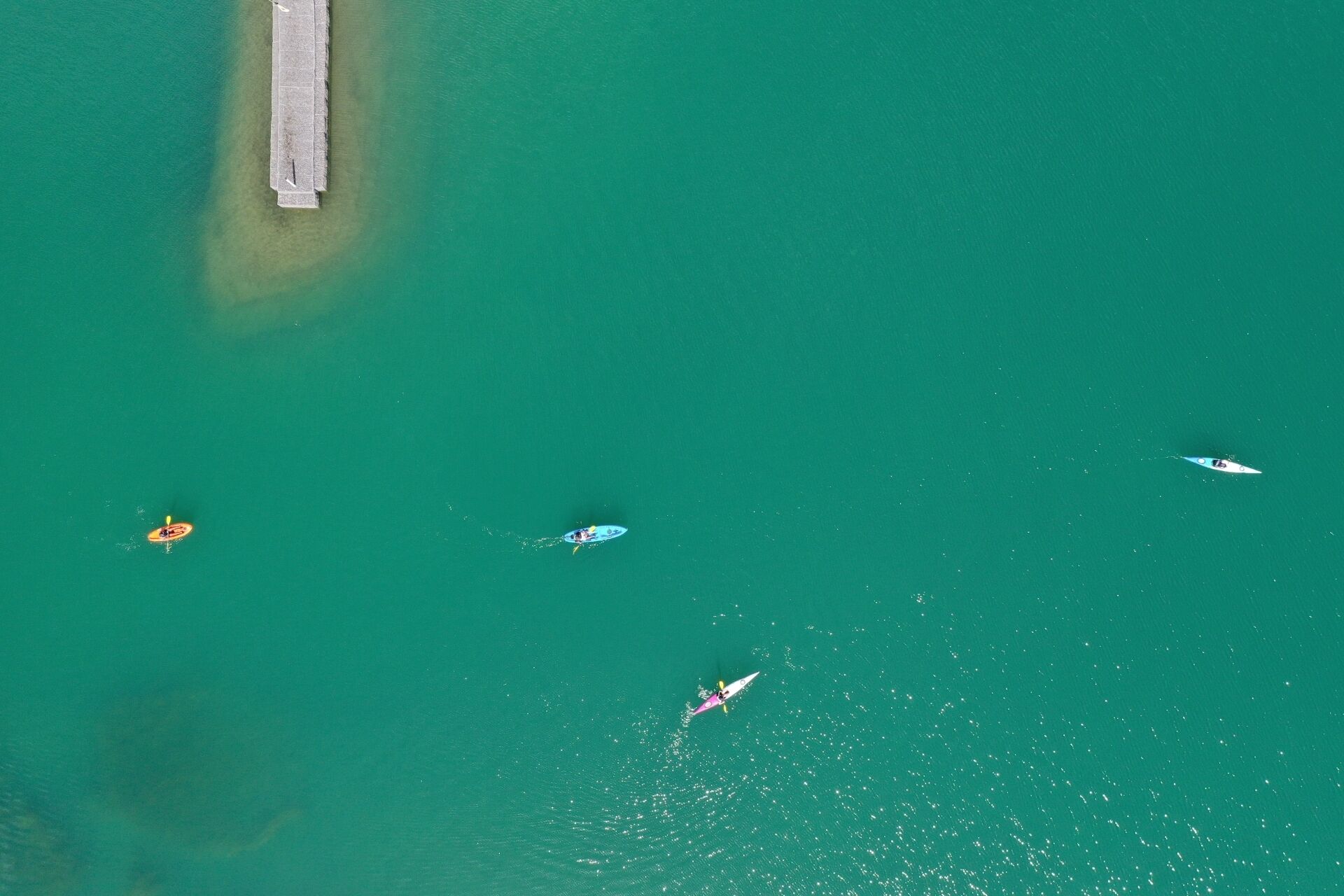 An aerial view of a coastal area with a pier and several boats.