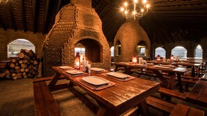 A rustic restaurant with brick arches, wooden tables, and benches. - First Group Qwantani (Maluti a Phofung)