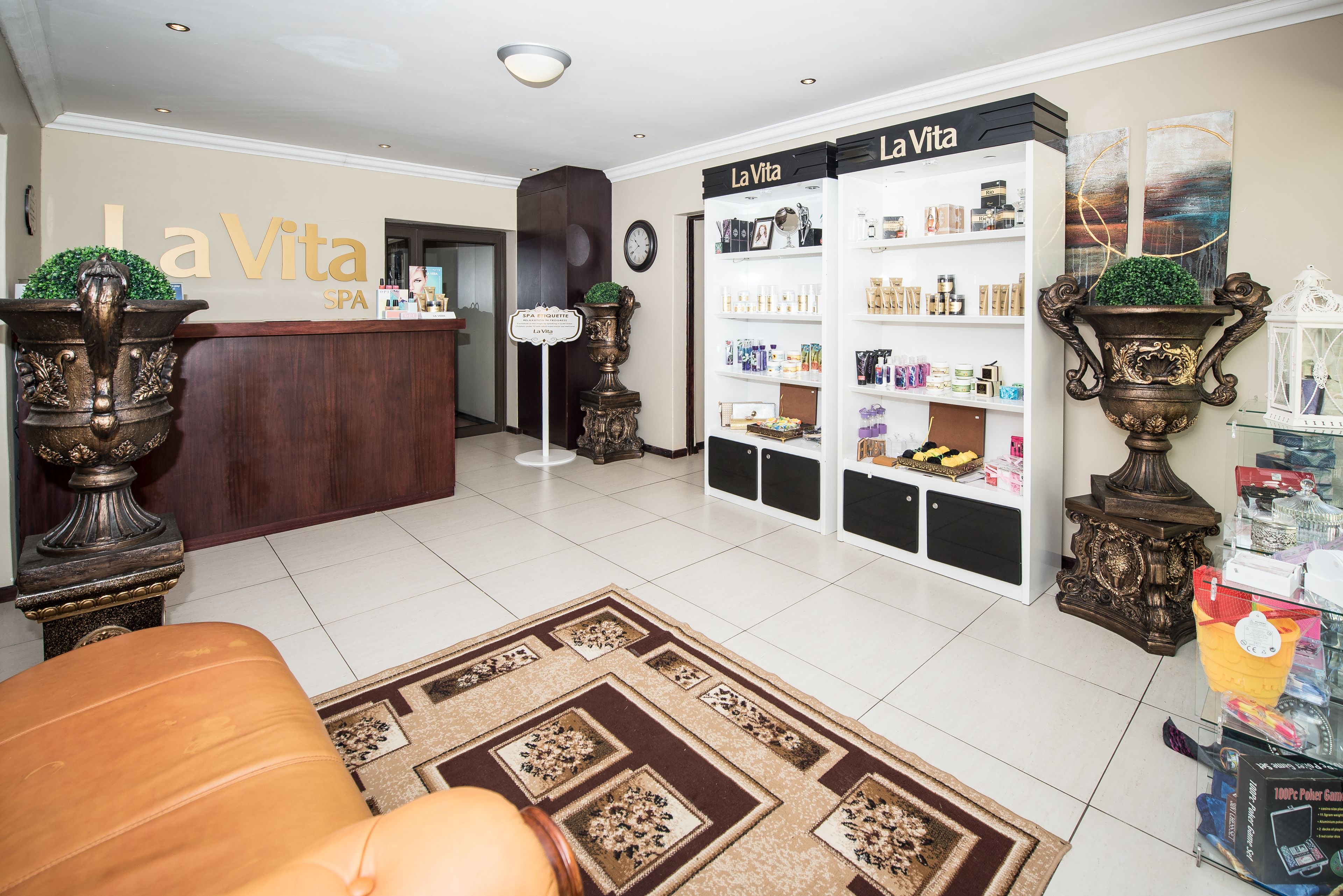 A spa reception area with a reception desk, a clock, and shelves stocked with spa products.