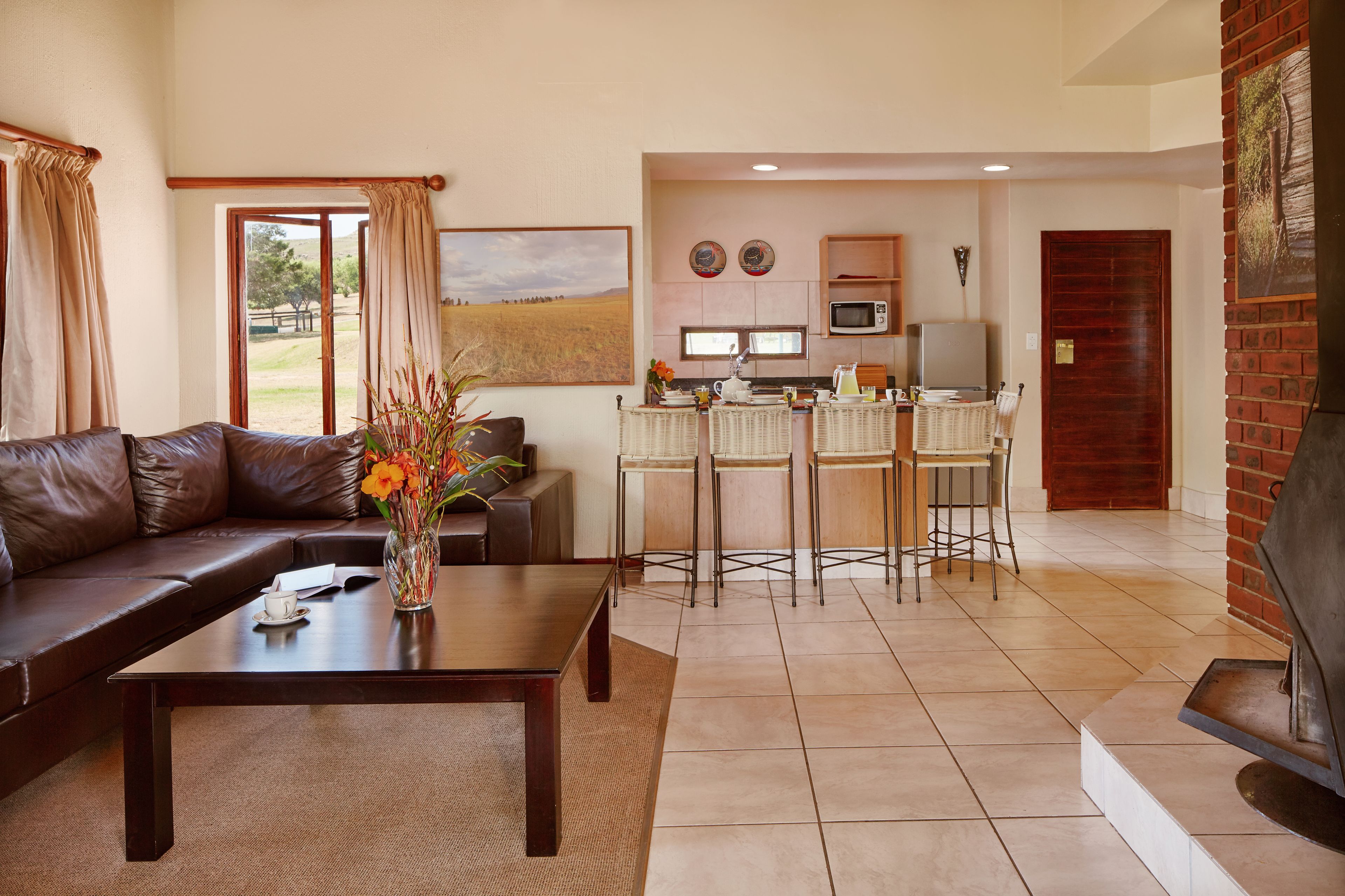 A living room with a brown leather sofa, a coffee table, and a dining area with a kitchen in the background.