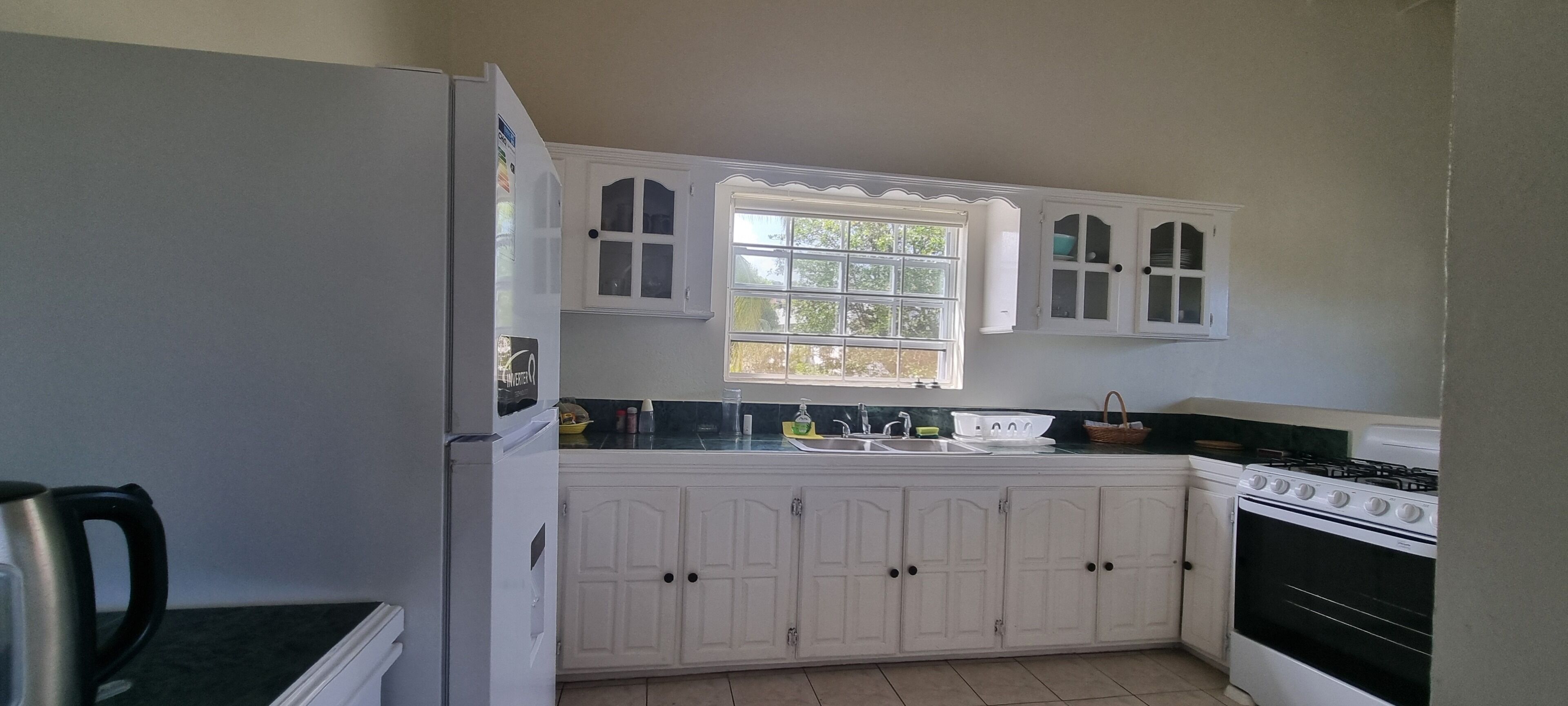 A kitchen with white cabinets, a sink, a stove, and a window.