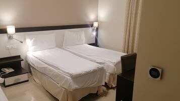 Habitación de hotel con dos camas, una mesita de noche con teléfono y lámparas fijadas a la pared.