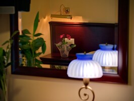 Een spiegel die een lamp, een bloemenvaas en een plant weerkaatst.