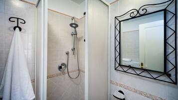 Un baño con ducha, perchero y espejo con marco decorativo.