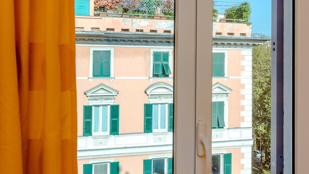 A window with a view of a building with green shutters and a balcony. - Hotel Boccascena (Genoa)