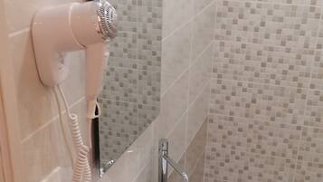 Un baño con un lavabo blanco, un espejo y un secador de pelo fijado a la pared.