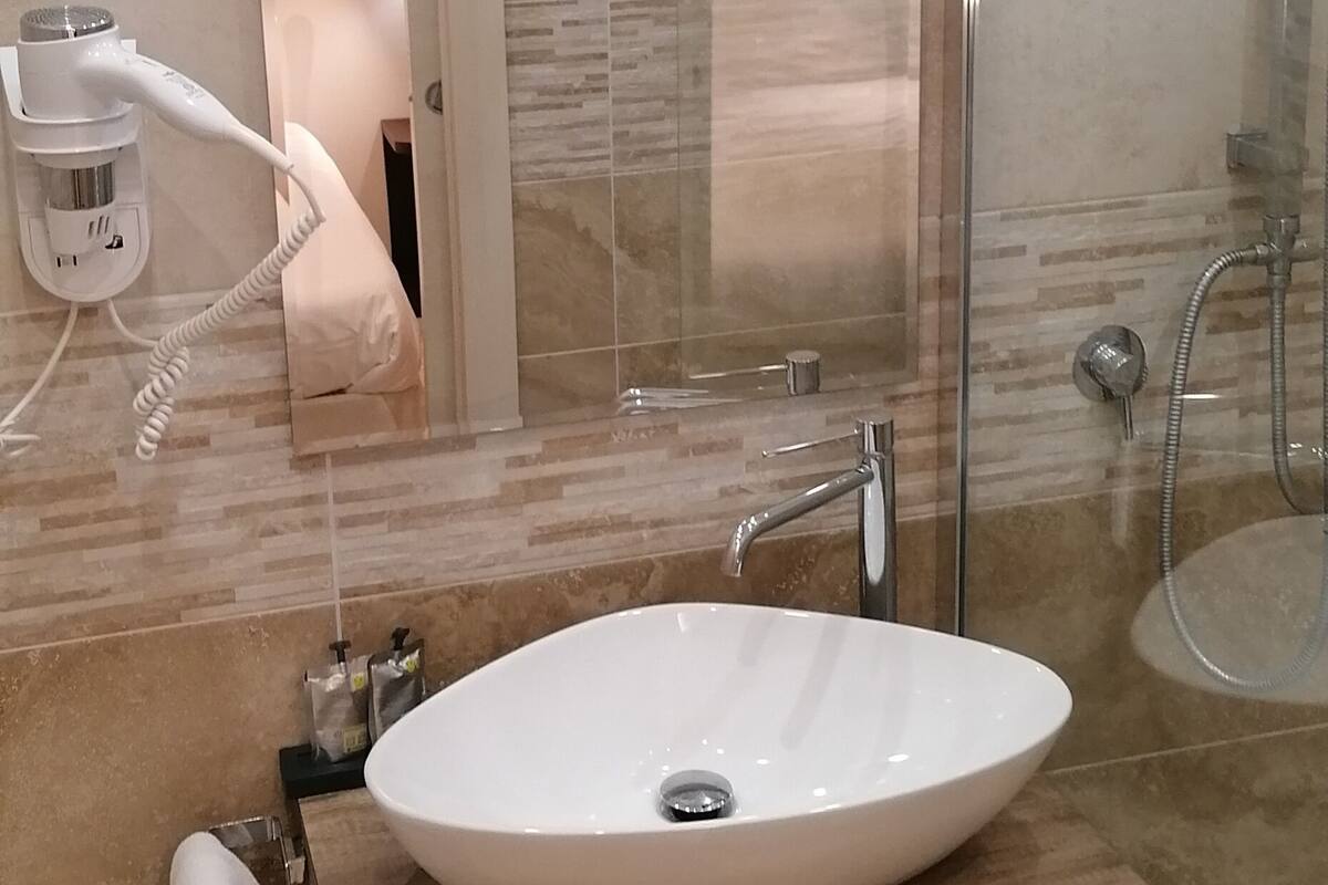 A modern bathroom with a large oval sink, a glass shower enclosure, and a mirror above the sink.