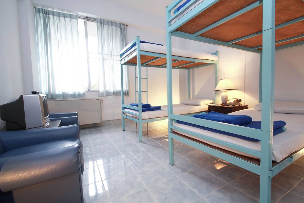 A dormitory room with bunk beds, a desk, and a chair.
