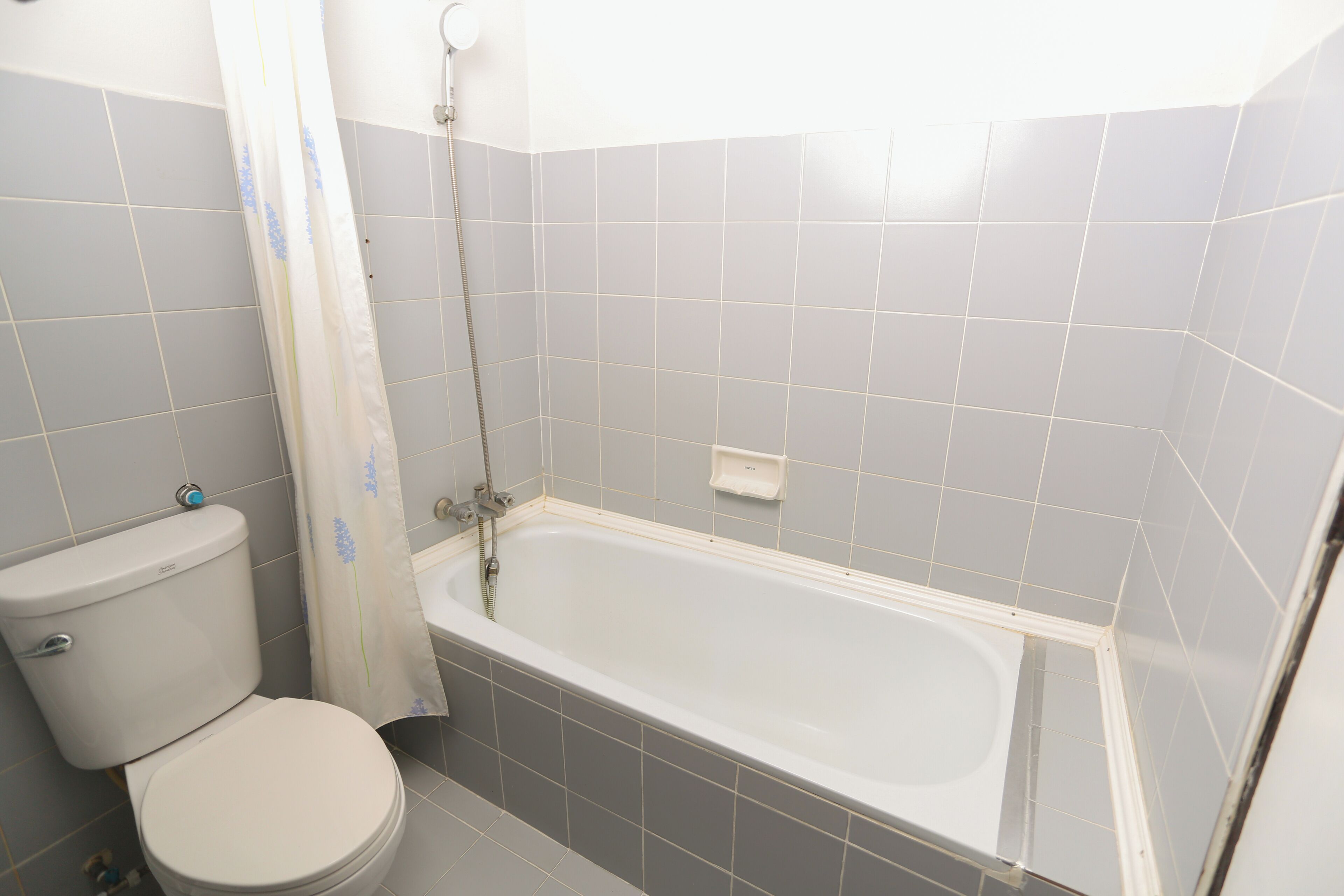 A bathroom with a toilet, bathtub, and shower curtain.