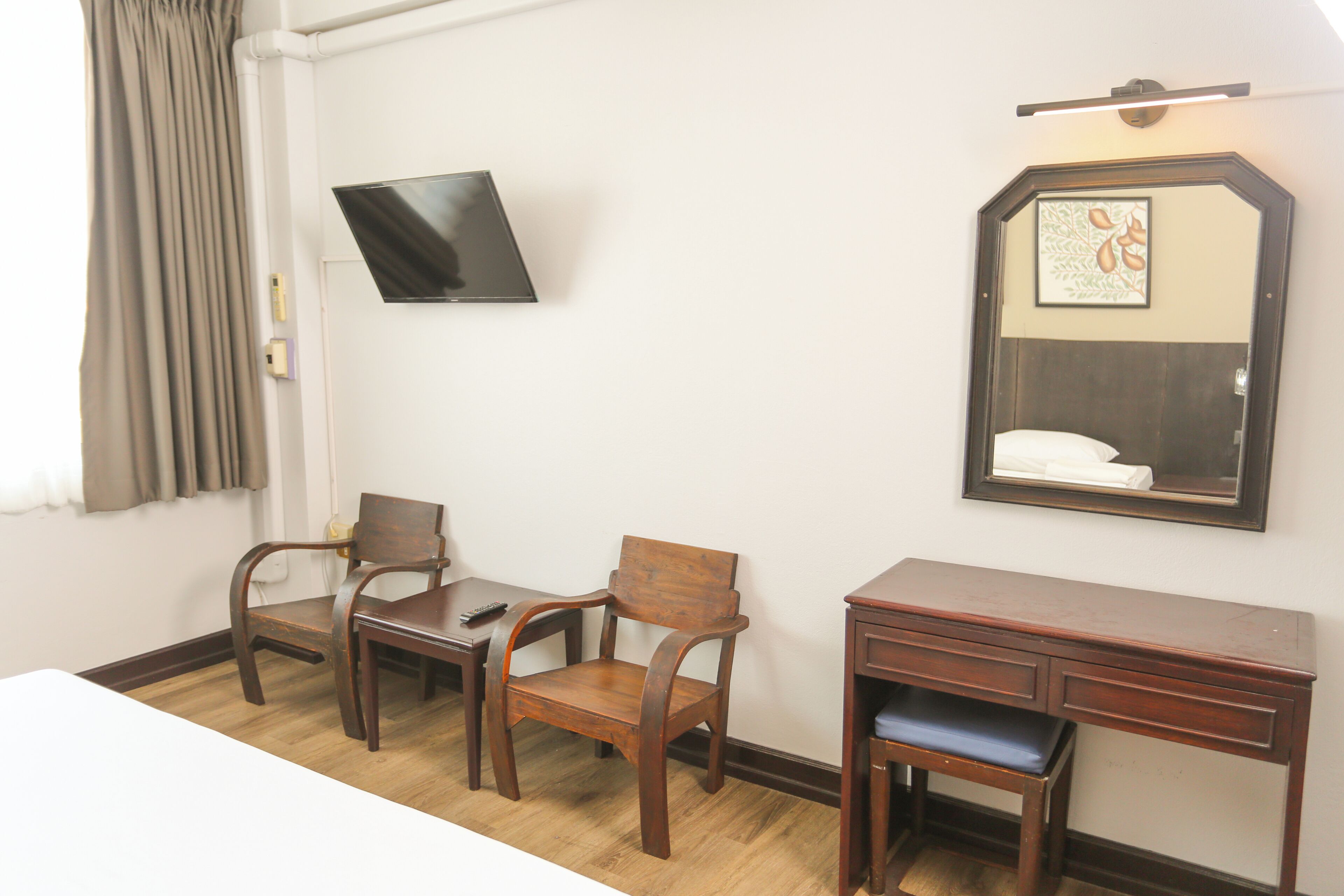 A hotel room with a wooden desk, two chairs, a television, and a mirror.