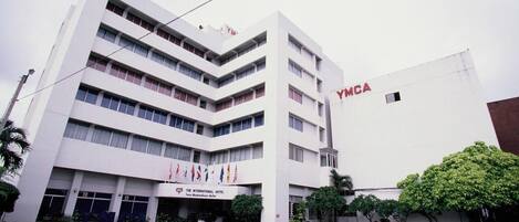 A multi-story building with a flat facade, a sign reading "YMCA", and a sign for "The International Hotel".