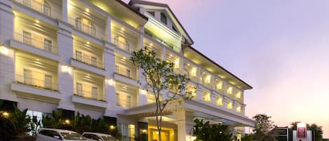 A multi-story hotel with a grand entrance, multiple balconies, and a well-lit facade.