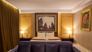 A hotel room with a large bed, two bedside tables, a painting of a temple, and a curtain. - Gallery Prawirotaman Hotel (Yogyakarta)