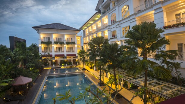 A large hotel with multiple balconies, a swimming pool, and lush greenery. - Gallery Prawirotaman Hotel (Yogyakarta)