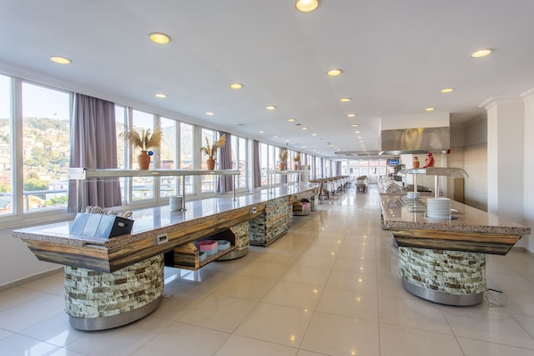 A spacious hotel lobby with a long reception desk, large windows, and a modern kitchen area. - Aslan City Hotel (Alanya)